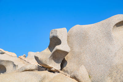 Low angle view of rocks against clear blue sky