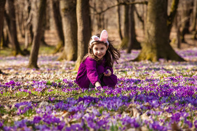 Portrait of girl with purple flowers on field