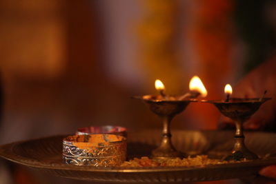 Close-up of illuminated diyas in plate on table