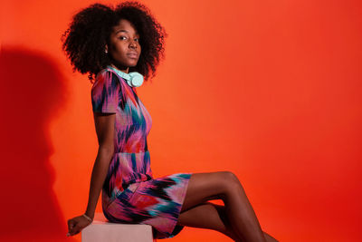 Portrait of woman standing against orange background