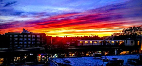 Illuminated buildings in city against sky at sunset