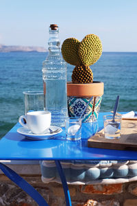Coffee cup on table by sea against sky