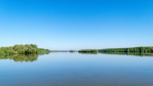 Scenic view of lake against clear blue sky