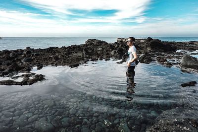 Man standing in sea against sky