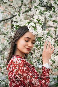 Smiling woman standing by tree