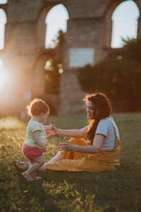 Mother and daughter on field during sunset