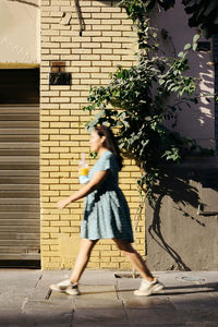 Side view of young woman standing against wall