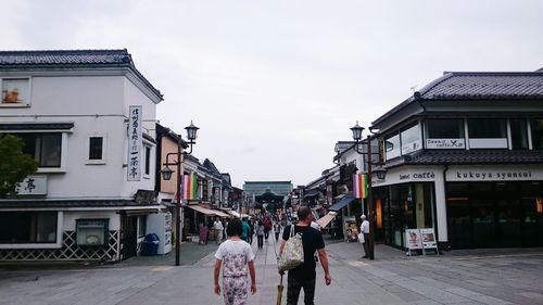 People walking on street in city against sky