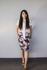 Young woman standing against wall