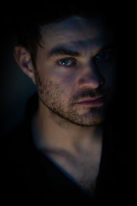 Portrait of young man against black background