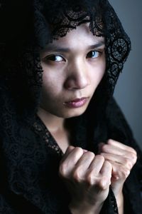 Close-up portrait of young woman wearing scarf against wall