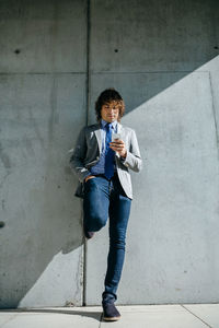 Full length of young man standing against wall