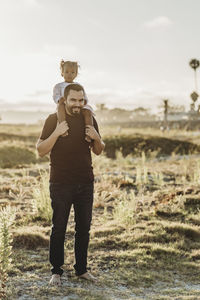 Portrait of young father and toddler girl smiling at the beach