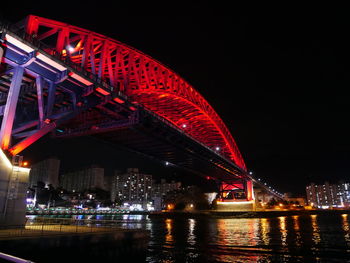 Low angle view of illuminated bridge over river at night