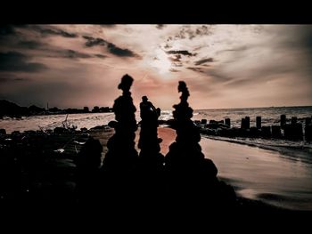 Silhouette people on beach against sky during sunset