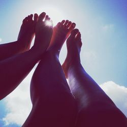 Low angle view of human feet against sky