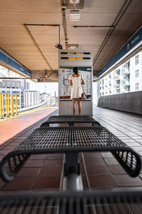 Rear view of woman reading map at railroad station