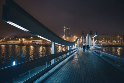 Illuminated bridge over river against sky in city at night