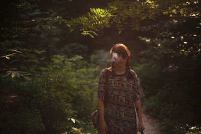 Young woman looking away while standing on tree