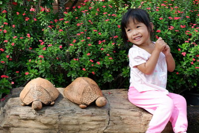 Cute girl sitting by tortoises against plants