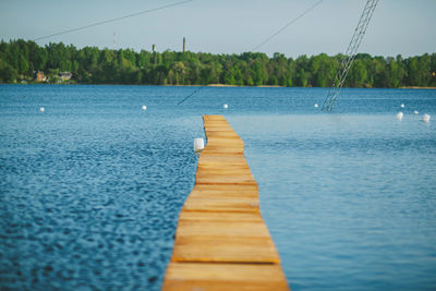 Surface level of wooden jetty in lake against blue sky