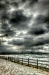 Pier on sea against cloudy sky