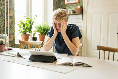 Young man studying with head in hands at home