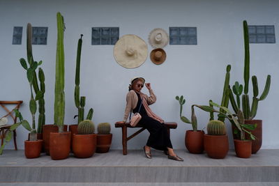 Portrait of young woman using mobile phone while standing against wall