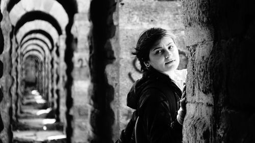 Side view portrait of young woman by wall in corridor