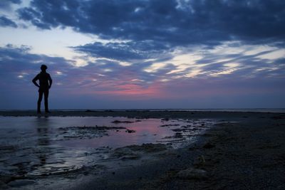 Silhouette man standing on beach against sky during sunset