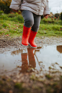 Low section of baby girl walking on puddle during rainy season