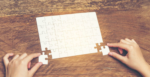 Cropped hands of woman playing jigsaw puzzle at table