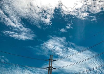 Low angle view of electricity pylon against blue sky