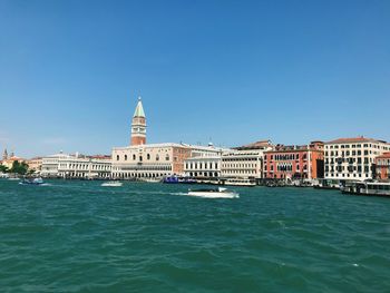 View of buildings by canal against clear sky