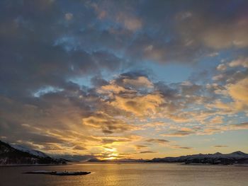 Scenic view of sea against dramatic sky during sunset