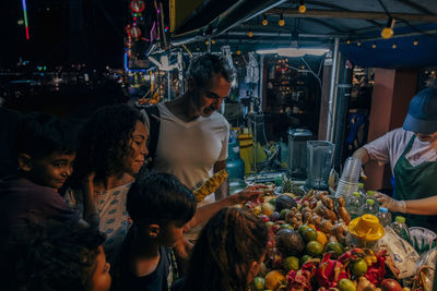 Family buying juice from fruit stall at food market on vacation