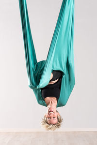 Portrait of happy aerialist performing on silk against wall