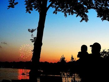 Silhouette trees by sea against sky during sunset