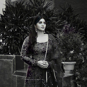 Portrait of young woman standing against wall