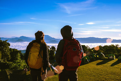 Rear view of people looking at mountains against sky