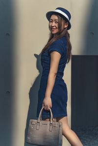 Portrait of young woman standing against wall