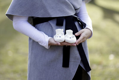 Midsection of pregnant woman standing on field