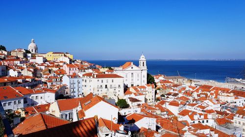 Houses in town by sea against clear sky