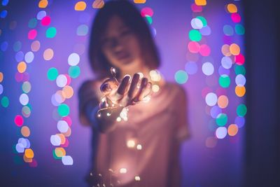 Close-up of woman holding illuminated string lights