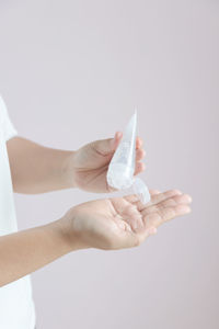 Close-up of woman holding hands over white background