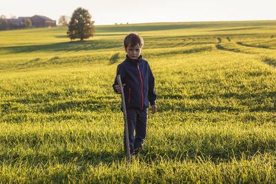 Portrait of cute boy standing on grassy land