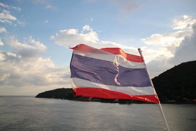 Scenic view of flag by sea against sky