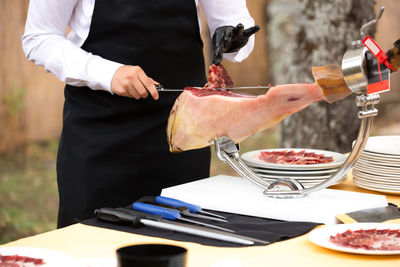 Ham cutter with gloves at a party cutting thin slices of iberian ham