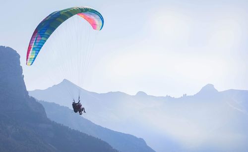 People paragliding over mountain against sky