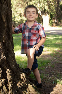 Portrait of boy smiling on tree trunk